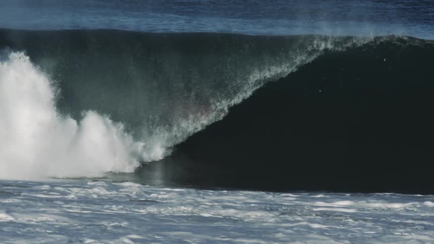 A surfer rides inside the barrel of a powerful ocean wave showcasing skill and balance against a dramatic natural backdrop