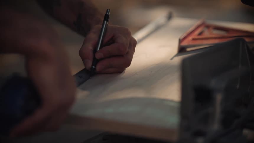 A person uses a ruler and pen to make precise measurements on a work surface likely engaging in a craft construction or trade task