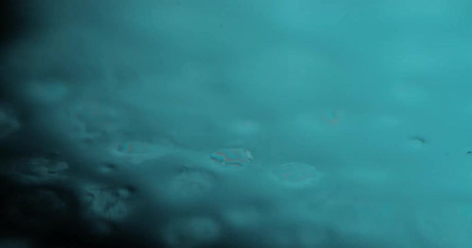 Closeup of a bluish surface with liquid droplets