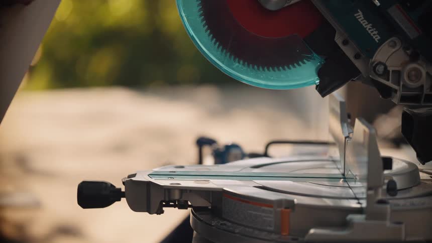 Closeup of a man removing a wooden plank from an electrical saw to a worktop