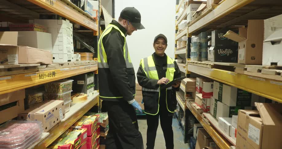 Two workers are laughing and talking in the aisle