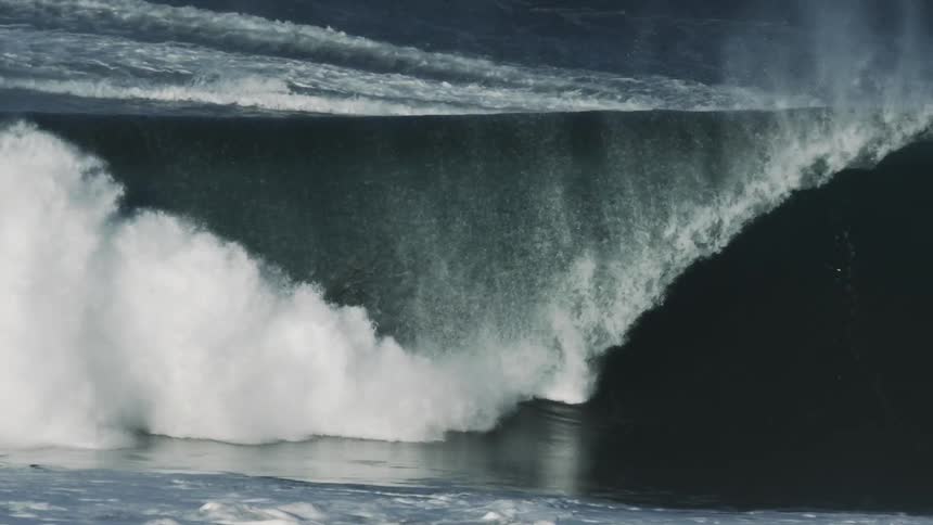 Surfer rides a huge waves as it curls overhead and covers him with water