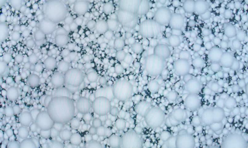 A smooth cgi animation shows a dense field of soft white spheres gently shifting in fluid organic motion
