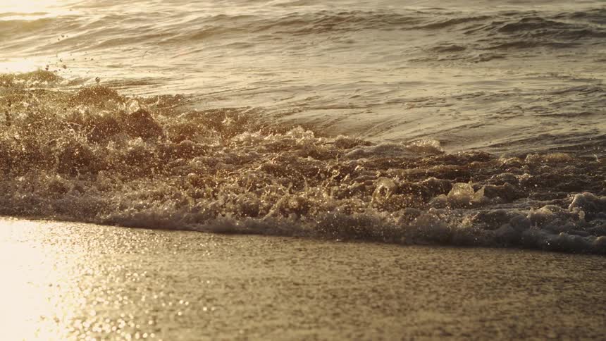 The rising sun is reflecting on the water on the beach
