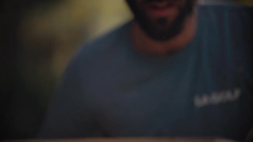 Man blowing off wood dust on a rectangle piece of lumber