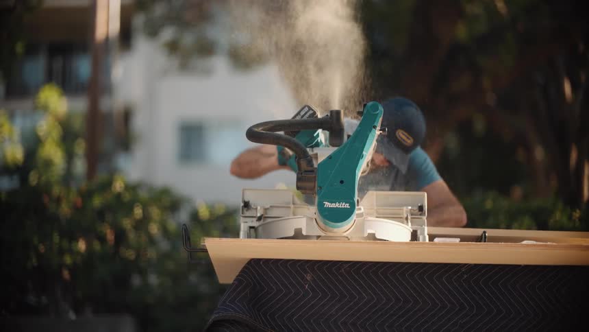Man using a table saw to cut wood outdoors