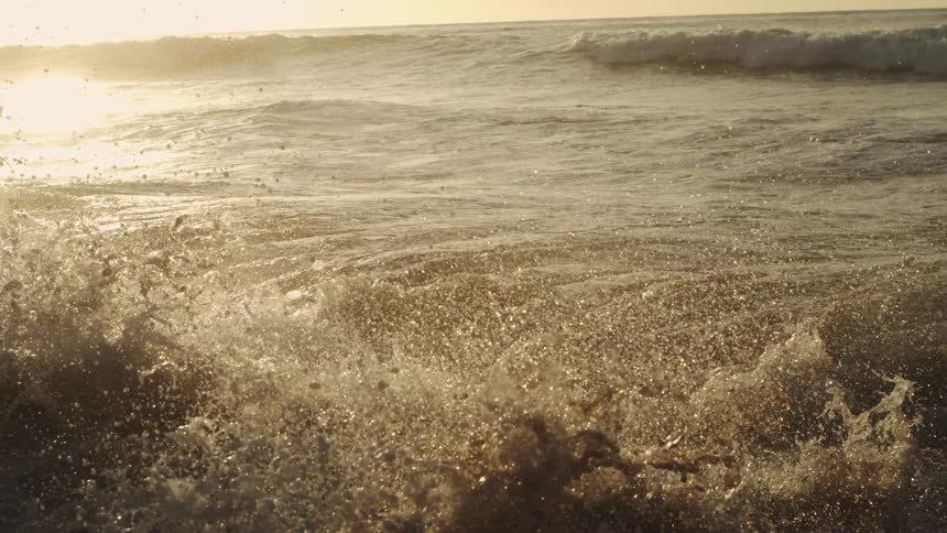 A wave splashing on the shore at sunrise