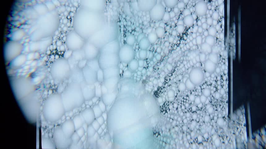 A highly magnified view of a surface filled with clustered white bubbles creates an abstract ethereal texture