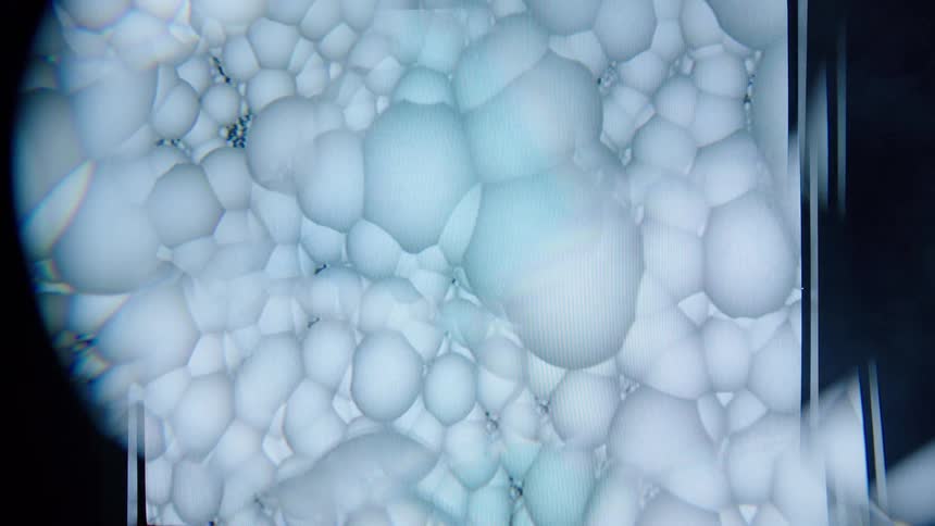 A series of white small balls flowing inside a magnifying glass chamber