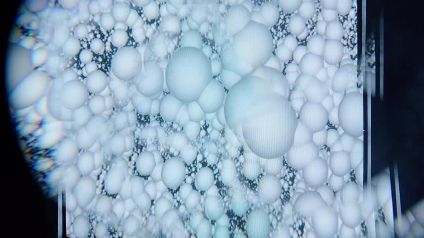 Round whitish particles against a black background