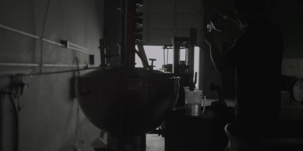 A worker measures out water in a factory setting