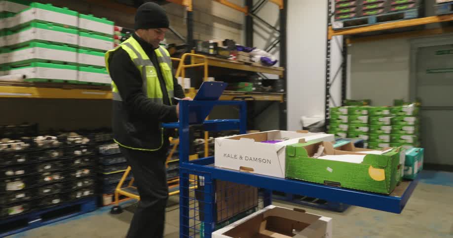 A worker wheels a cart full of boxes in the warehouse
