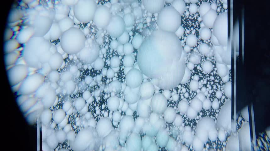 A series of white balls flowing inside a glass chamber