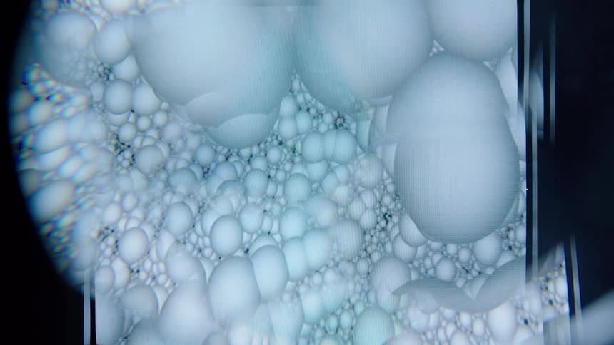 Bubbles or spherical structures viewed under magnification fill the frame in a soft blue tone creating a highly abstract scientific appearance