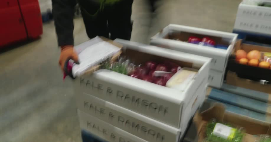 Worker picks and arranges a box on a pile of similar boxes
