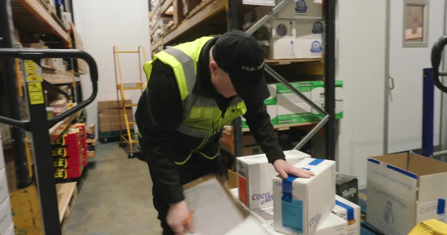 A worker reads and records details on a box in a sheet of paper