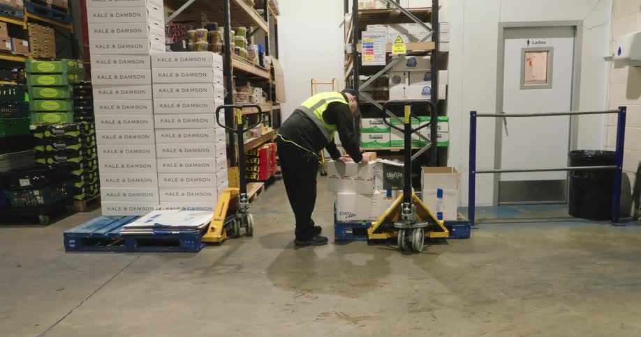 The employee is looking through a crate in the warehouse
