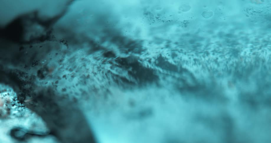 Small translucent bubbles sink through the water near a brown and pale blue surface
