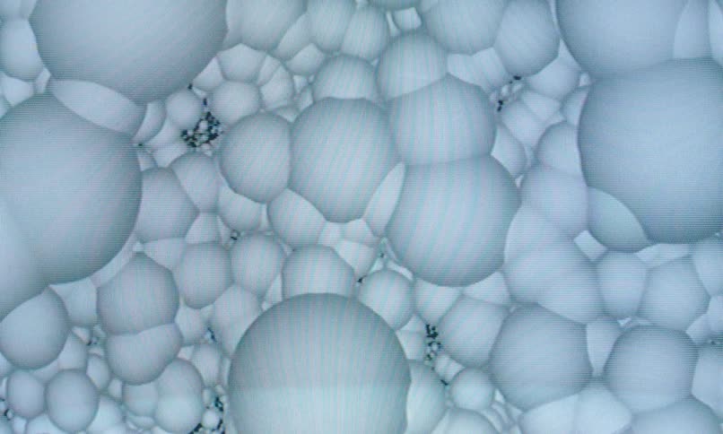 An extreme closeup of translucent white bubbles or spheres creates an abstract organic texture that resembles a microscopic or cgi visualization