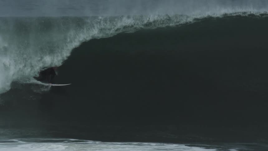 A man is surfing on a very large wave