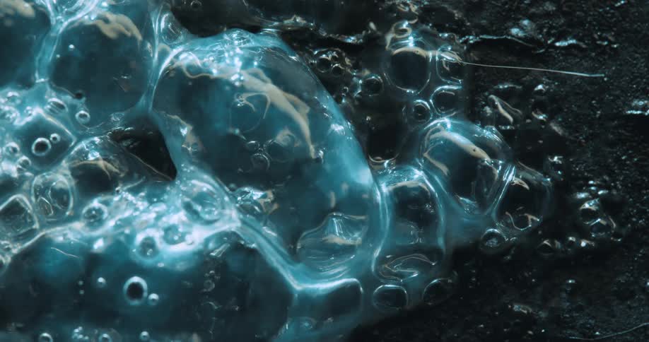 Blue translucent liquid bubbling on a black surface