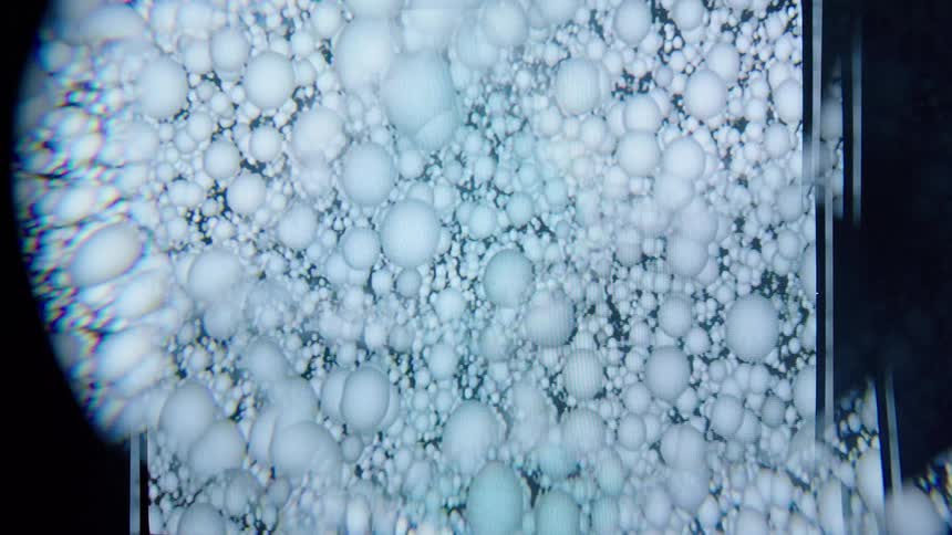 A closeup of a digital display shows layered circular forms resembling translucent bubbles through multiple exposures