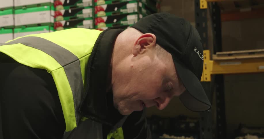 A warehouse worker inspects and writes on a clipboard while conducting inventory checks in a storage facility