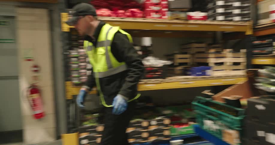 Male worker moves boxes of produce from a pallet and onto a cart