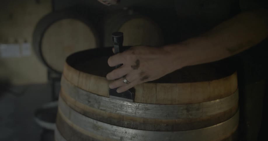 Person pounding a lid on top of a wooden barrel
