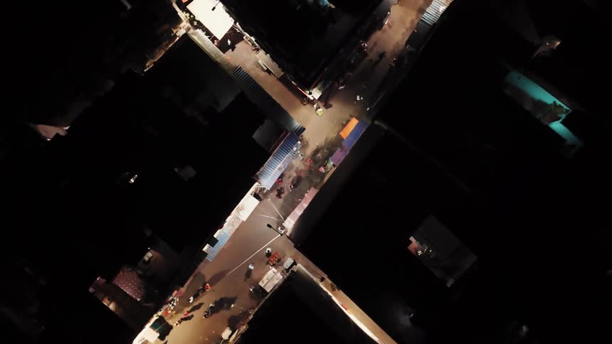 A neighborhood with a busy street filled with many people walking and some motorcycles