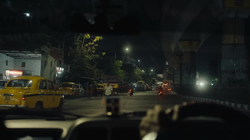 The taxi is driving down the road at night