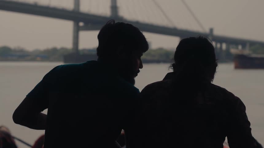 A man and woman talk together by the shore