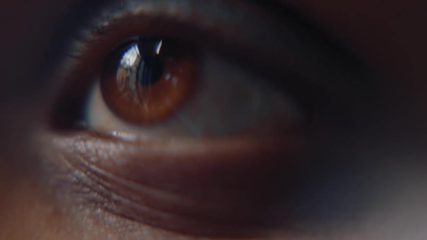 Blue eye shadow lines the upper lid of a person with an amber brown eye