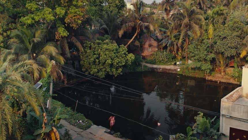 Person on the edge of a river tank surrounded by tropical vegetation