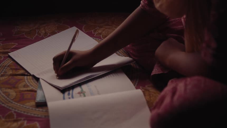 Child sitting on a rug writing on a sheet of paper