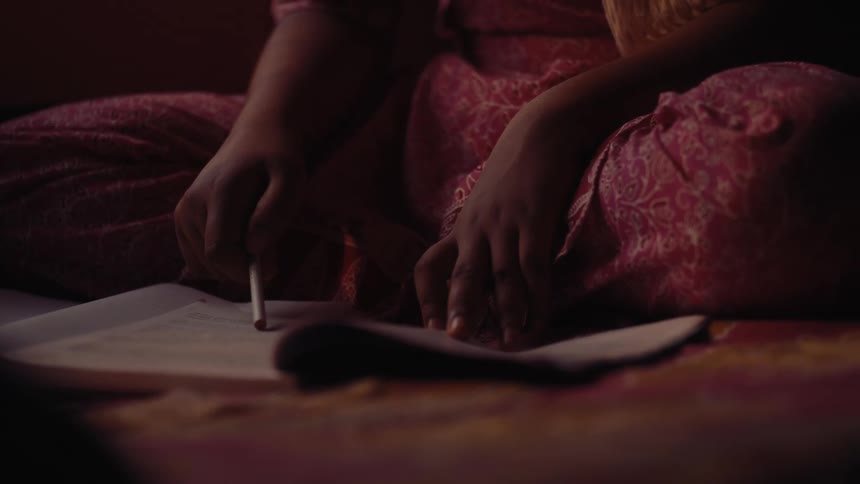 A girl is reading from a book while sitting on the floor