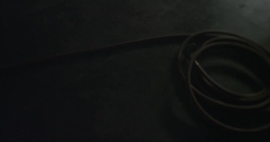 Earbud wires rolled up on a table in the dark