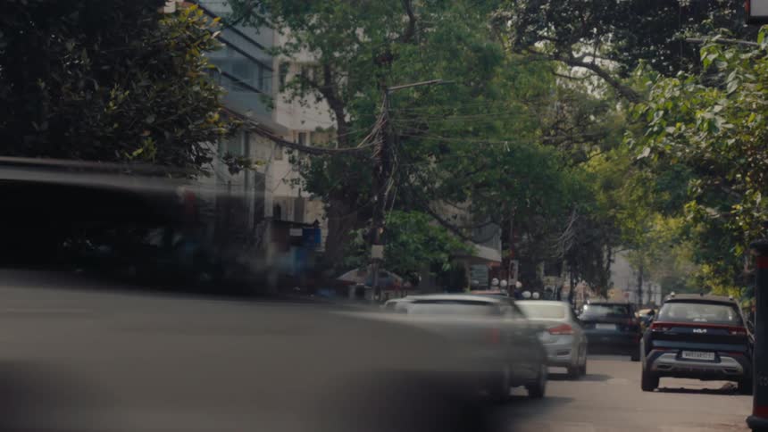 People cross the street in between cars driving down the road in a city