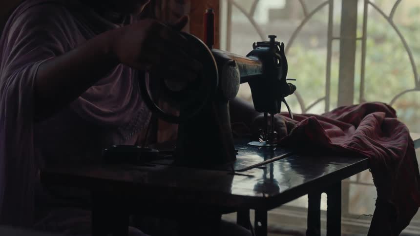 Woman sews a piece of clothing using a manual sewing machine