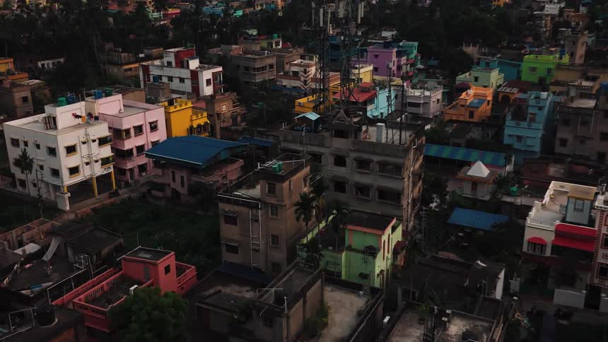 A colorful aerial view of a dense urban neighborhood with vibrant lowrise buildings in soft evening light