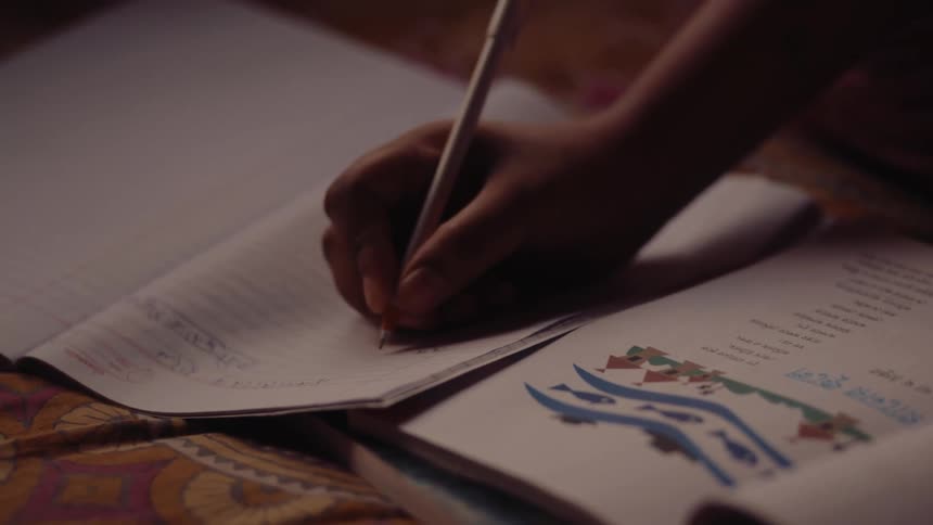 Person sitting studying and writing in a notebook
