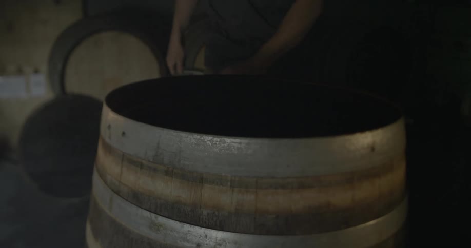 A man is taking the iron rings off of a wooden barrel