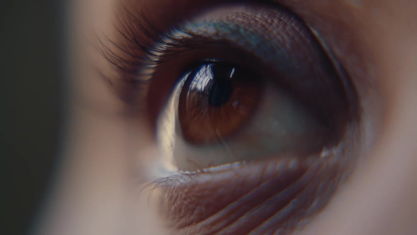 A persons eye with a brown iris opening and then looking straight ahead and blinking again