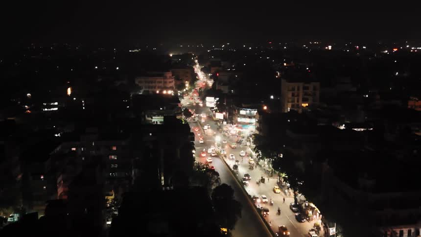 A nighttime aerial view of a busy city street with heavy traffic and illuminated buildings