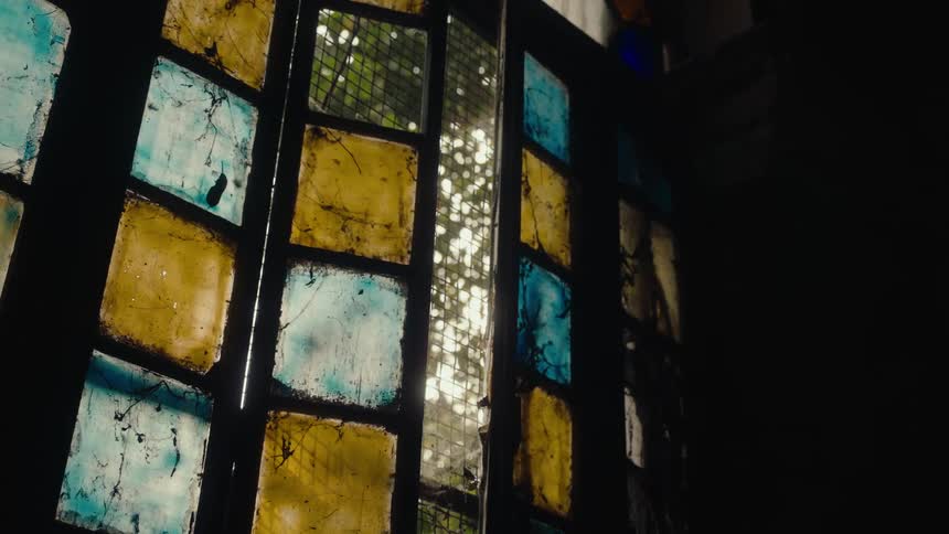 Interior view of a stained glass window with sun reflection