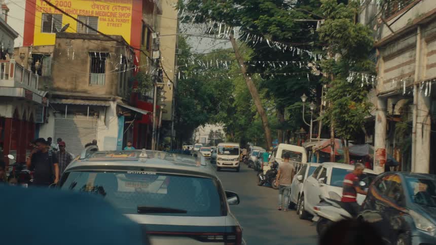Vehicles and pedestrians move up and down a busy street during the day