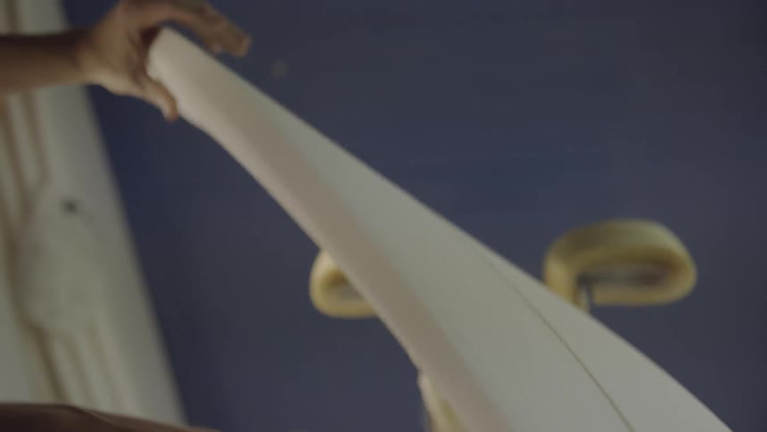 A man swiping at and turning a surfboard he is making