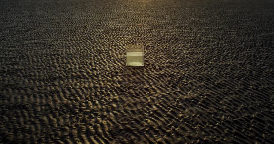 Transparent box with water on wet sand