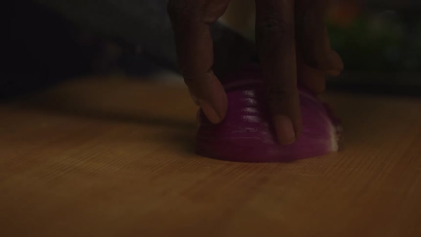 A woman uses a knife to cut up the red onion