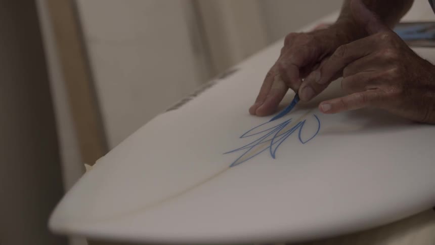 A person paints on a surfboard